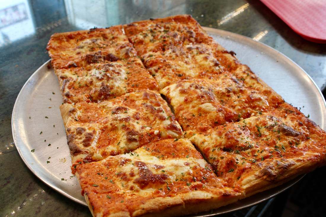 Square pizza with melted cheese and herbs
